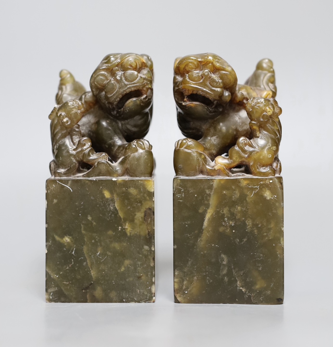 A pair of Chinese soapstone lion dog seals, 15 cms high